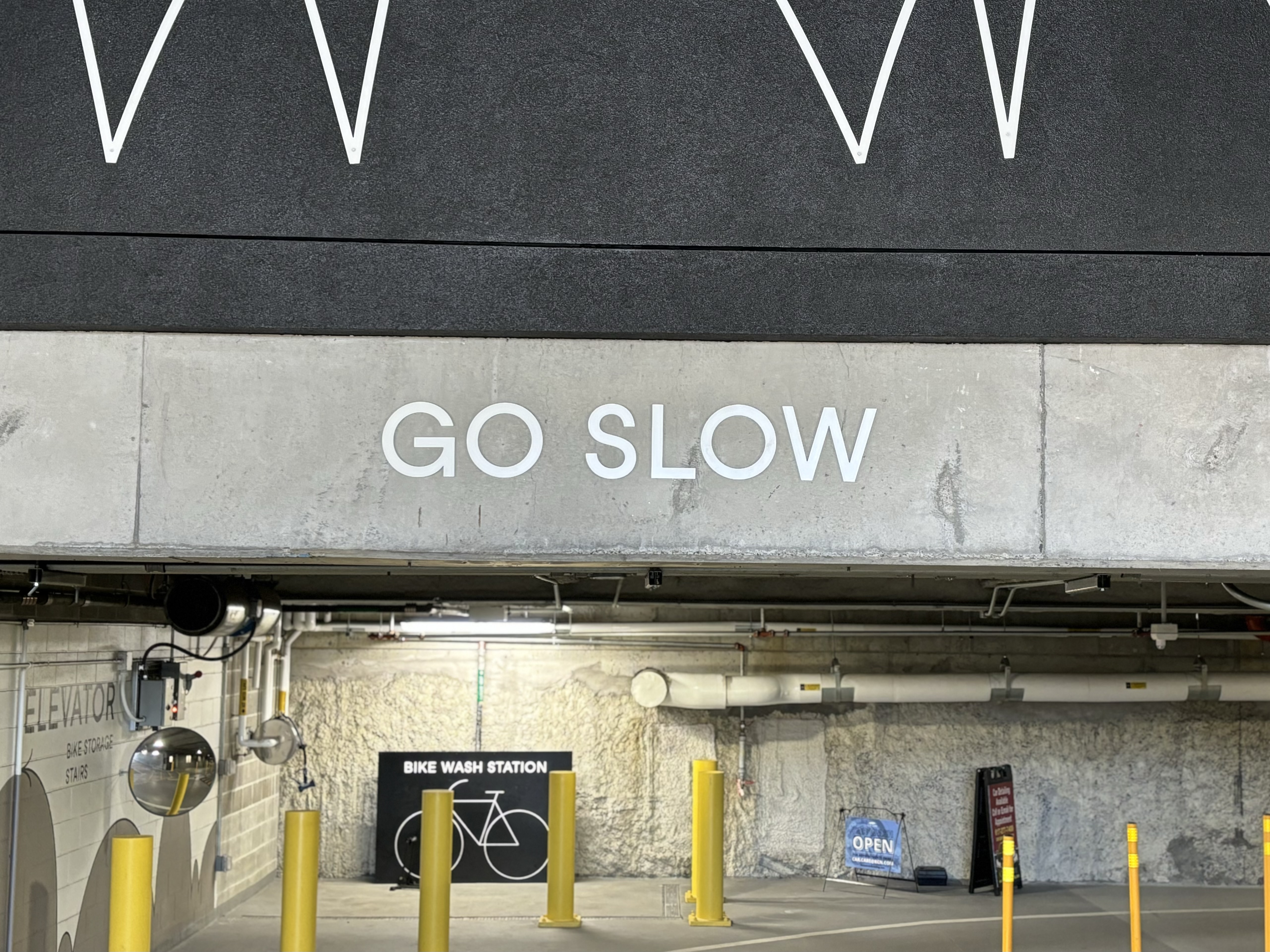 Parking garage sign that commands us to 'GO SLOW'.